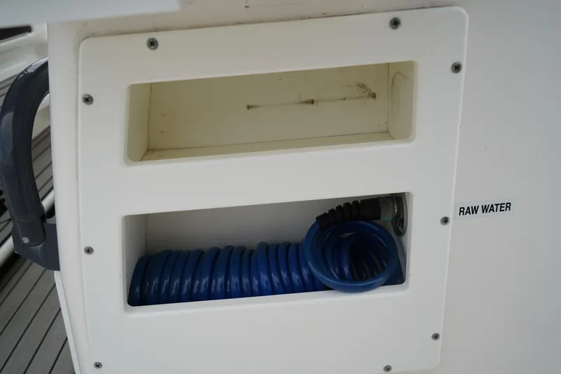 Slide: The Image of 2020 Sea Fox 328 Commander raw water hose storage compartment with blue coiled hose. - 21