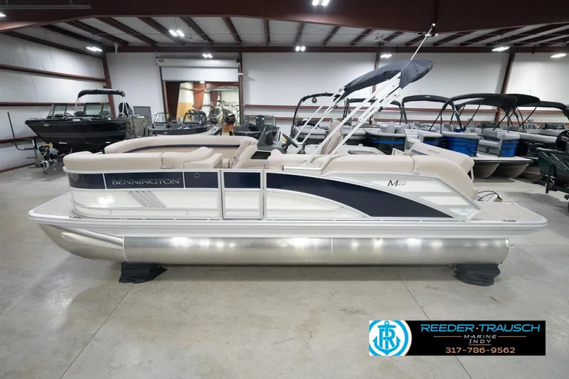 Slide: The Image of 2026 Bennington 22 ML pontoon boat in showroom, side view, with canopy and seating. - 63