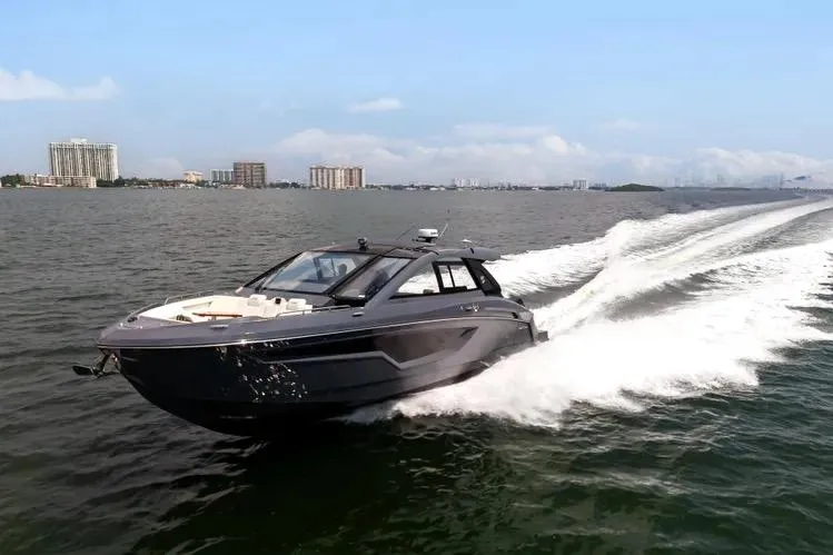 The Image of 2023 Cruisers 42 GLS OB yacht speeding on open water, cityscape in background. - 0
