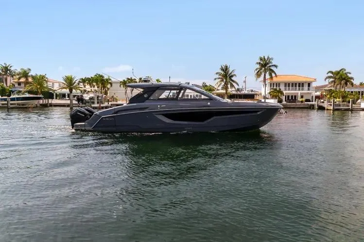 Slide: The Image of 2023 Cruisers 42 GLS OB yacht on water, surrounded by palm trees and waterfront homes. - 9