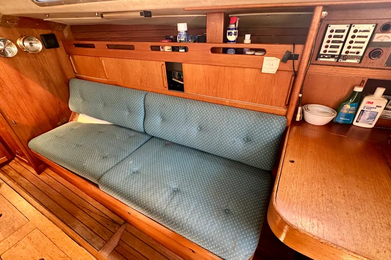 Slide: The Image of 1983 Sirena 38 yacht interior with blue cushioned seating and wooden cabinetry. - 11