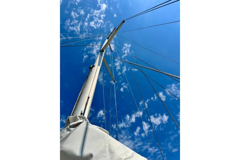 Slide: The Image of Mast of 1983 Sirena 38 sailboat against a bright blue sky with clouds. - 28
