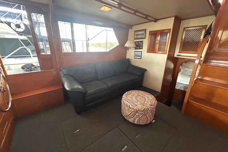 Slide: The Image of 1988 CHB Ponderosa Motor Yacht interior with black sofa, patterned ottoman, and wooden accents. - 8