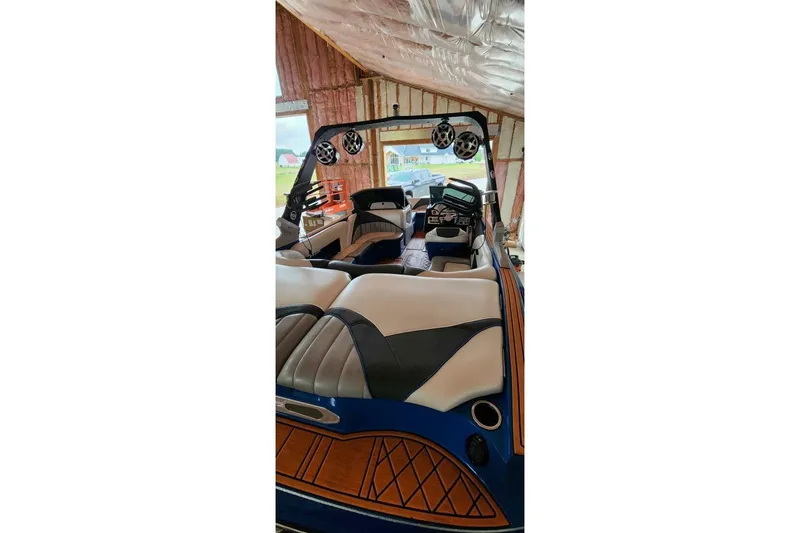 Slide: The Image of 2017 MB F21 boat interior with speakers, cushioned seats, and wood accents in a garage. - 6