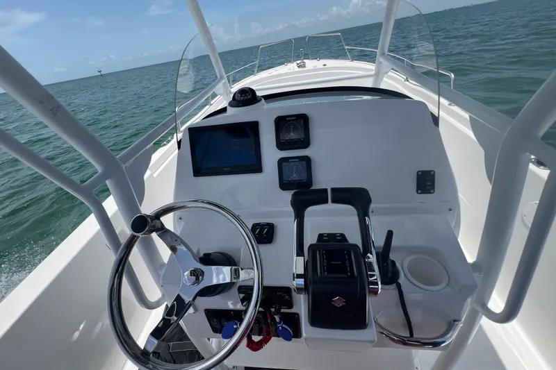 Slide: The Image of 2024 Yamane Center Consoles boat dashboard with steering wheel and navigation controls on open water. - 11
