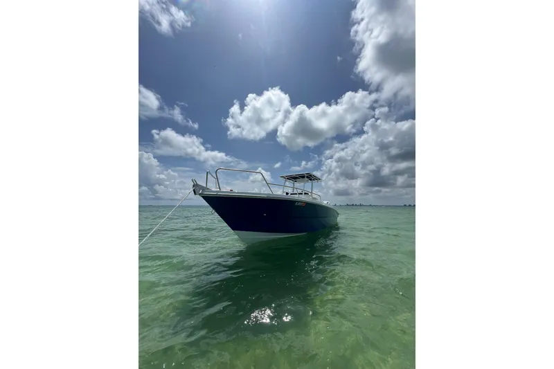 Slide: The Image of 2024 Yamane Center Consoles boat anchored in clear turquoise water under a partly cloudy sky. - 2
