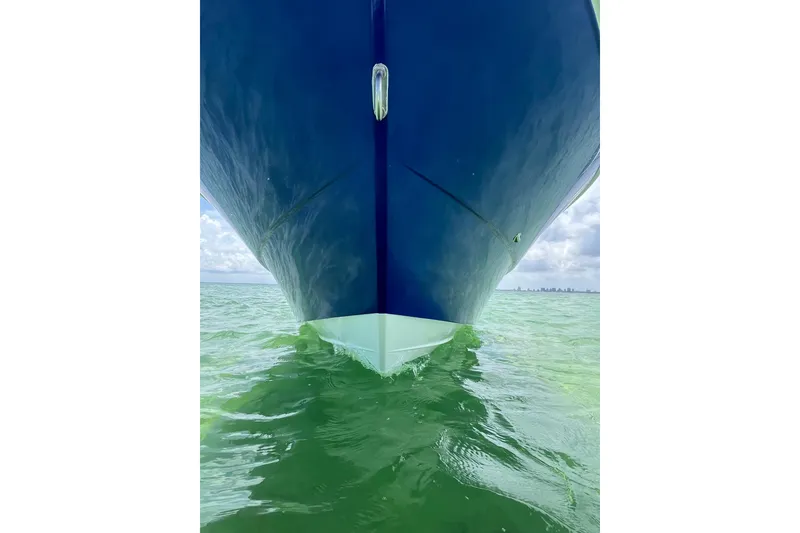 Slide: The Image of 2024 Yamane Center Consoles boat on calm green water, viewed from the front. - 6