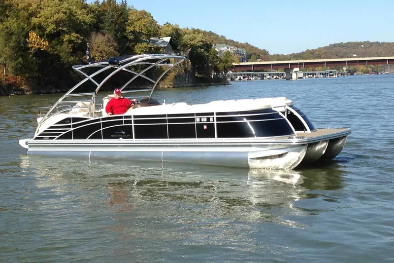 Slide: The Image of 2014 Bennington 2875 QCW I/O pontoon boat docked, featuring spacious seating and scenic lake view. - 1
