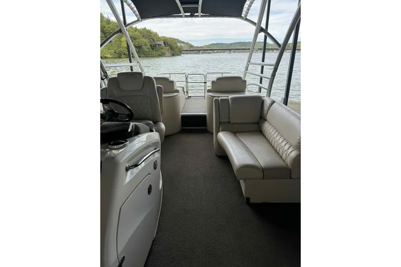 Slide: The Image of 2014 Bennington 2875 QCW I/O pontoon boat interior with seating and helm, on a scenic lake. - 13