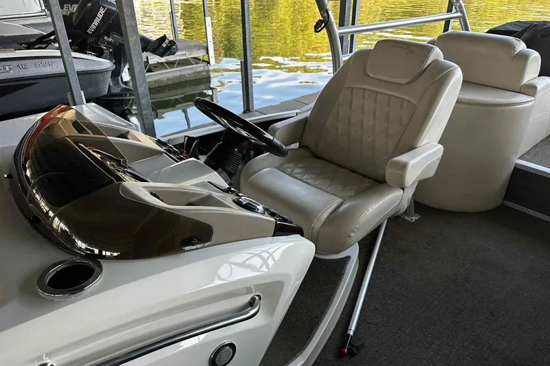 Slide: The Image of Captain's seat and helm of 2014 Bennington 2875 QCW I/O boat, docked by water. - 9