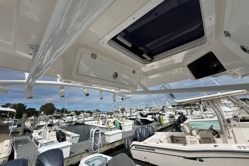 Slide: The Image of 2021 Sea Fox 288 Commander at marina, showcasing overhead storage and rod holders. - 27