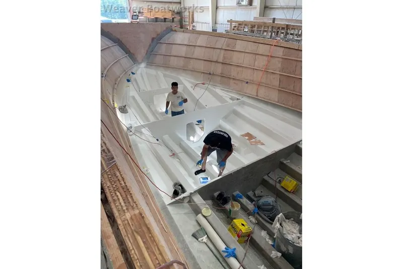 Slide: The Image of Workers constructing a 2025 Weaver Sportfish boat hull in a workshop. - 5