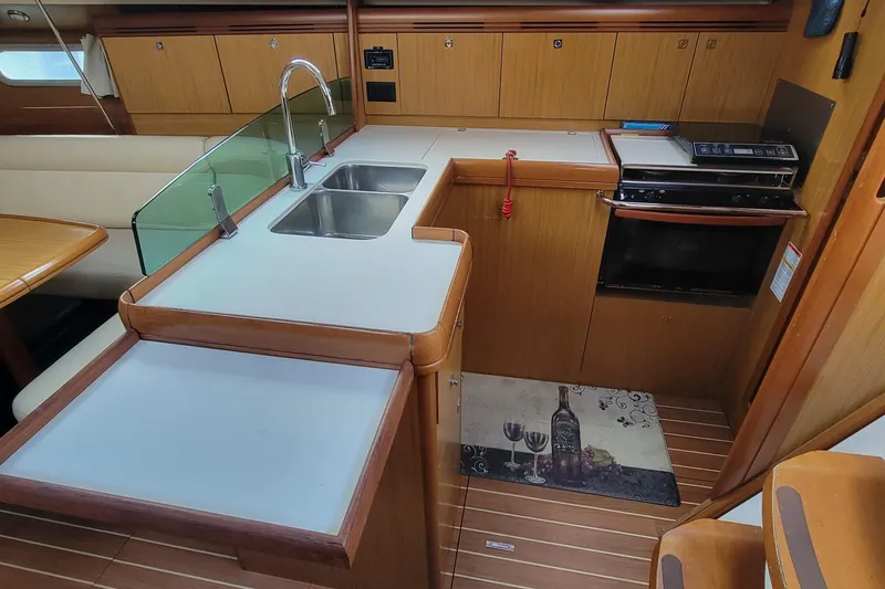 Slide: The Image of 2008 Jeanneau Sun Odyssey 42 DS yacht kitchen with sink, stove, and wooden cabinetry. - 16