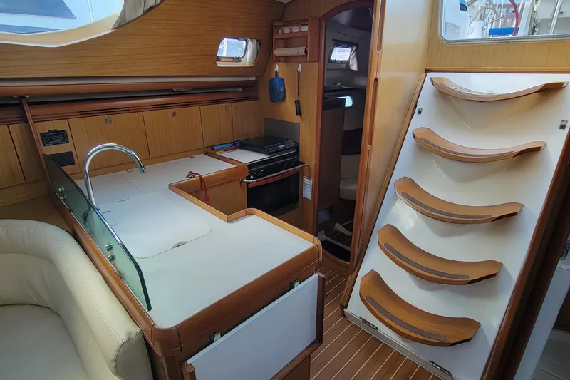 Slide: The Image of Interior of 2008 Jeanneau Sun Odyssey 42 DS yacht, featuring a compact kitchen and wooden stairs. - 6