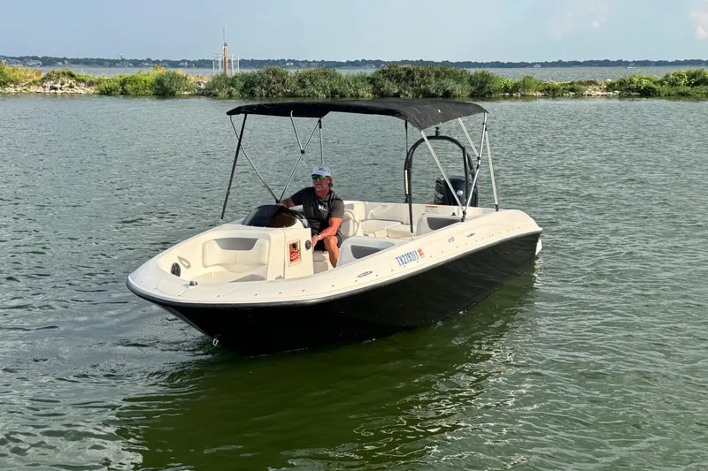 Slide: The Image of 2020 Bayliner Element E18 boat on water with canopy and driver. - 1