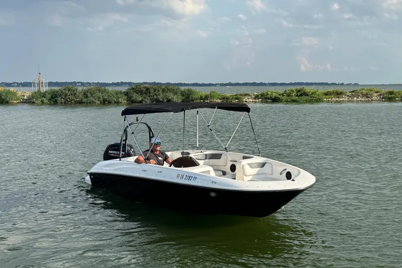 Slide: The Image of 2020 Bayliner Element E18 boat on a calm lake with lush green shoreline. - 2