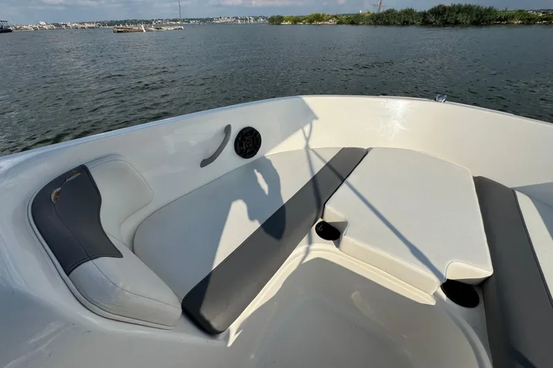 Slide: The Image of 2020 Bayliner Element E18 boat interior with cushioned seating, on a calm water backdrop. - 6
