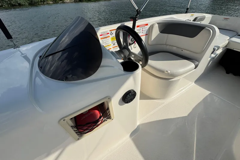 Slide: The Image of 2020 Bayliner Element E18 boat interior with steering wheel and seating, on a calm lake. - 9