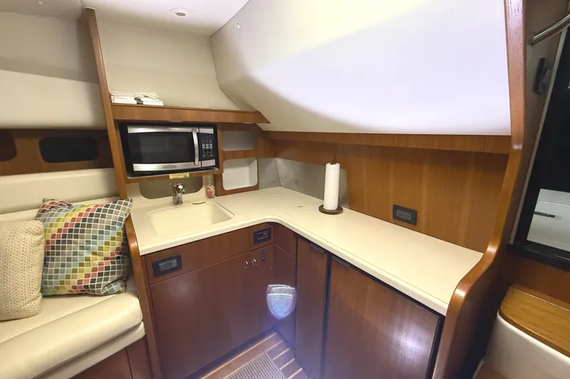 Slide: The Image of 2006 Tiara Yachts 3800 Open interior with kitchenette, microwave, and colorful cushions. - 28