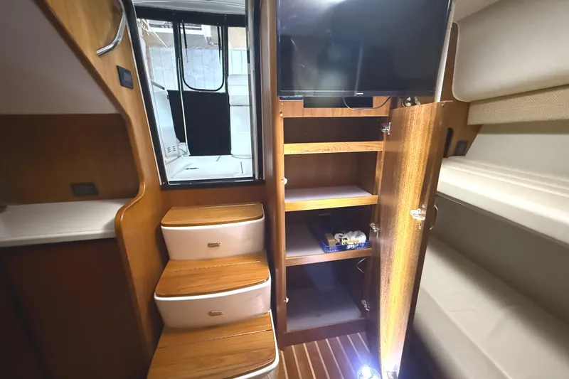 Slide: The Image of Interior of 2006 Tiara Yachts 3800 Open, featuring wooden steps, storage, and a mounted TV. - 37