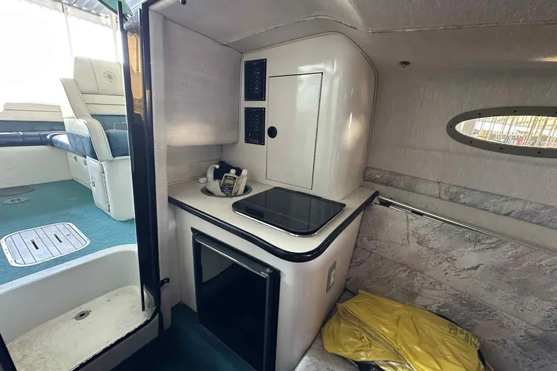 Slide: The Image of Interior of a 1995 Genesis Boats 2505, featuring a compact kitchenette and seating area. - 13