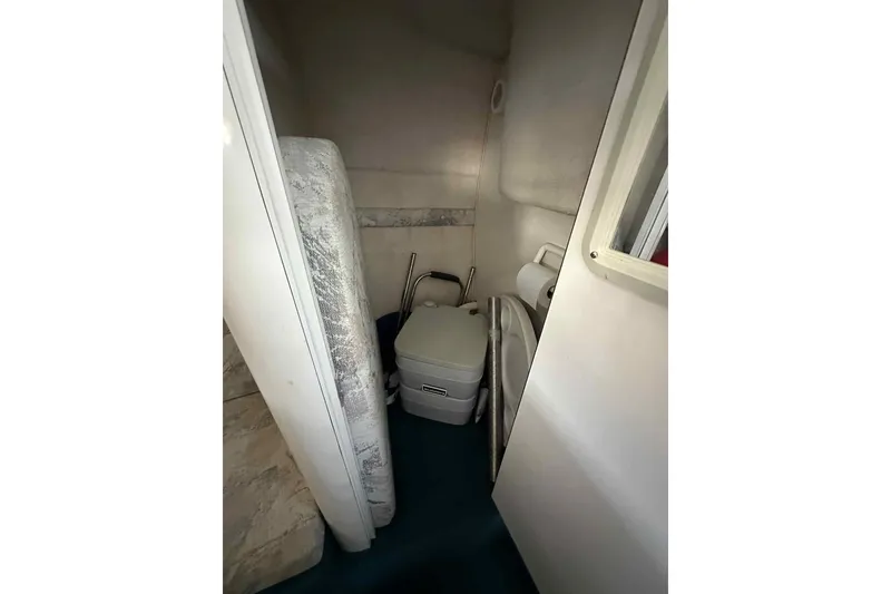Slide: The Image of Interior of 1995 Genesis Boats 2505, featuring compact bathroom with portable toilet. - 16