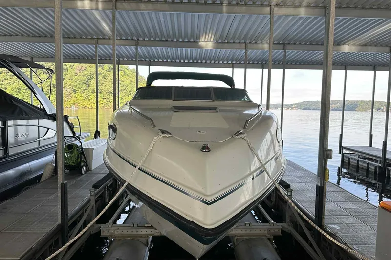 Slide: The Image of 1995 Genesis Boats 2505 docked in a covered marina with scenic lake view. - 19