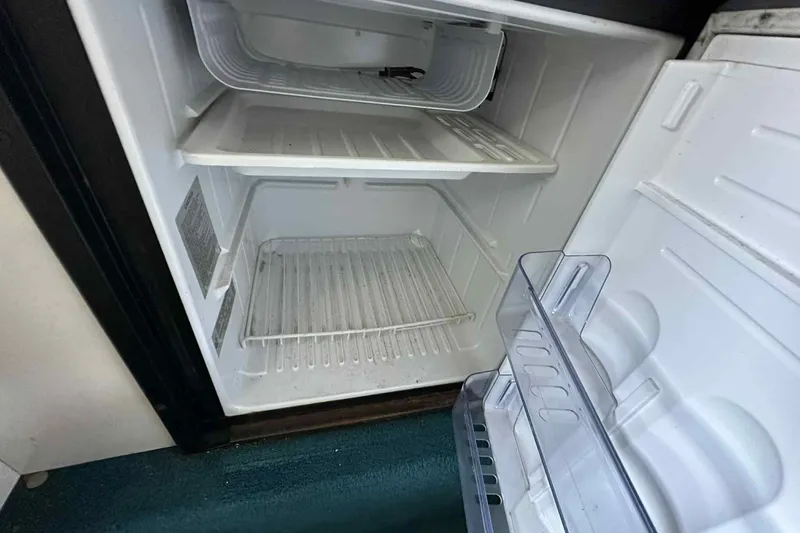 Slide: The Image of Open refrigerator inside a 1995 Genesis Boats 2505, showing empty shelves and door compartments. - 7