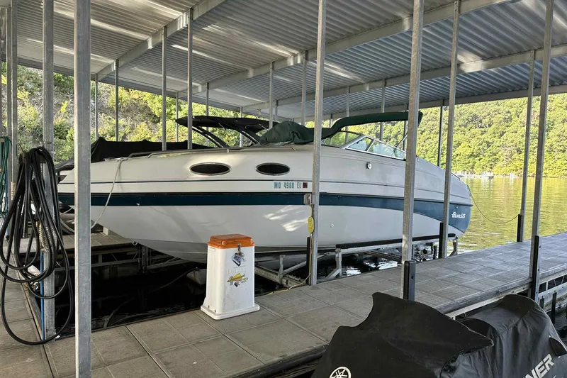 The Image of 1995 Genesis Boats 2505 docked under a covered marina with scenic lake view. - 0