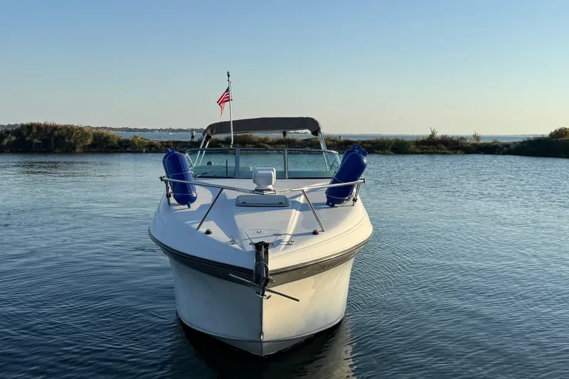 Slide: The Image of 2003 Crownline 262 CR boat on calm water with American flag. - 1