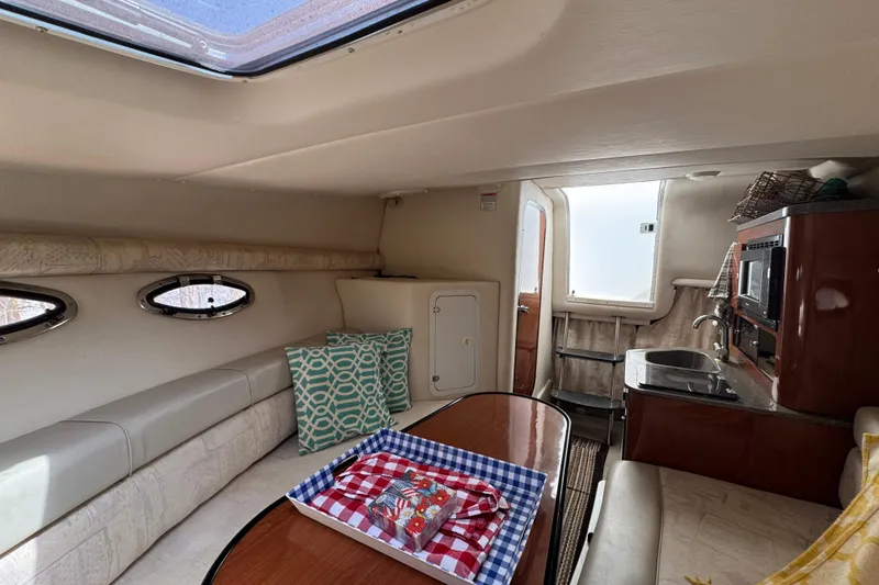 Slide: The Image of 2003 Crownline 262 CR cabin interior with kitchenette, seating, and decorative pillows. - 15