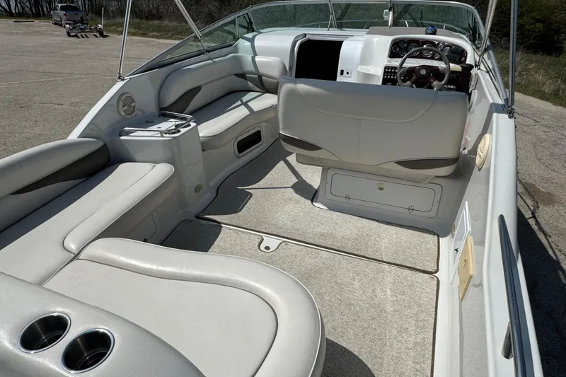 Slide: The Image of 2003 Crownline 262 CR boat interior with seating and steering wheel, parked on pavement. - 23