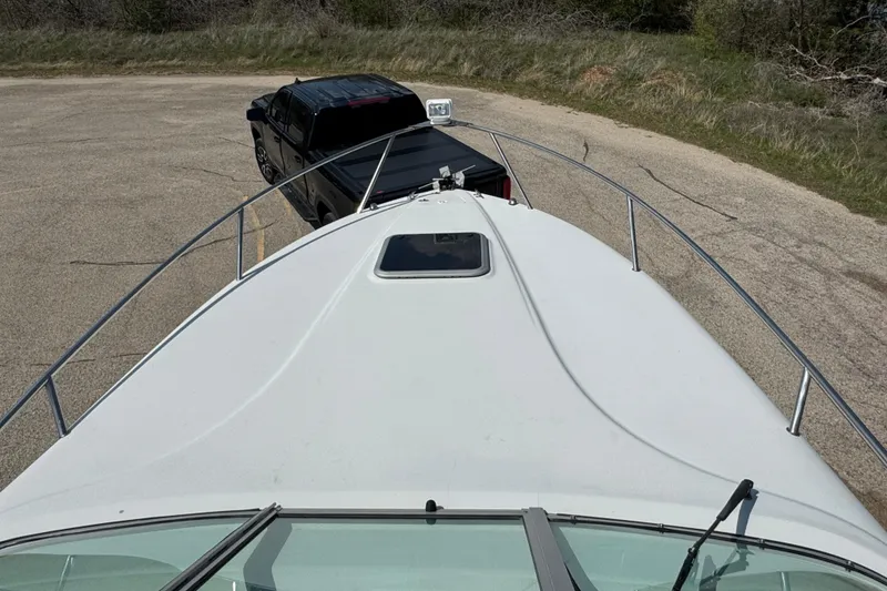 Slide: The Image of 2003 Crownline 262 CR boat on trailer, parked near black truck on paved road. - 26