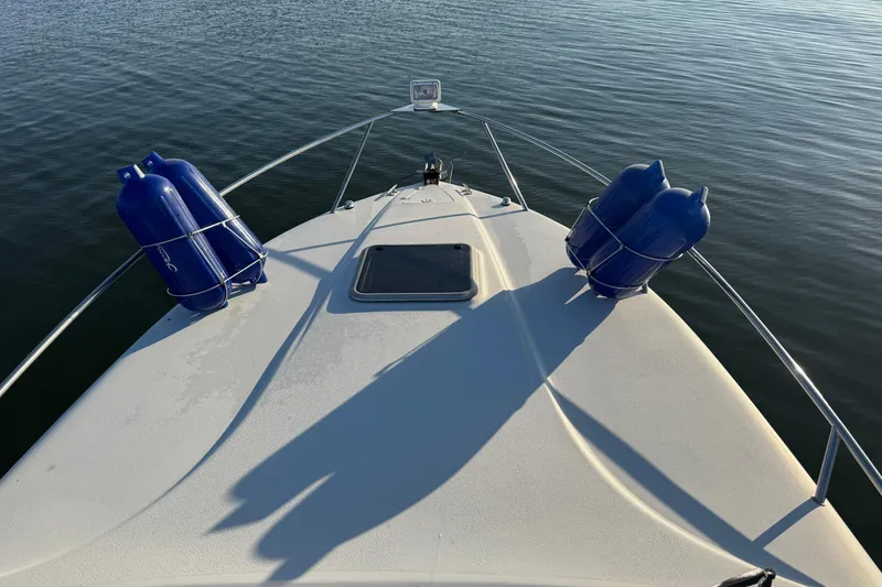 Slide: The Image of 2003 Crownline 262 CR boat deck with blue fenders on calm water. - 27