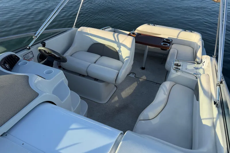 Slide: The Image of 2003 Crownline 262 CR boat interior with white seating and wooden table on calm water. - 28