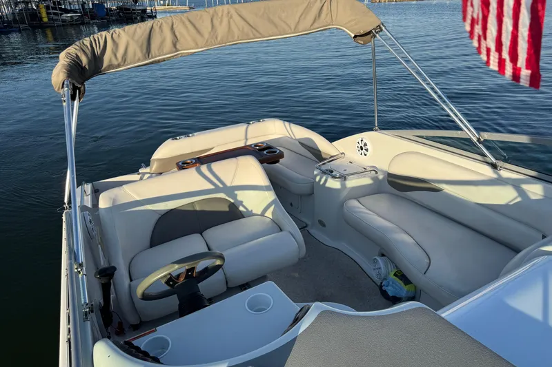 Slide: The Image of 2003 Crownline 262 CR boat interior with beige seating and steering wheel on calm water. - 29