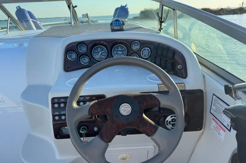 Slide: The Image of Steering wheel and dashboard of a 2003 Crownline 262 CR boat, with gauges and controls. - 31