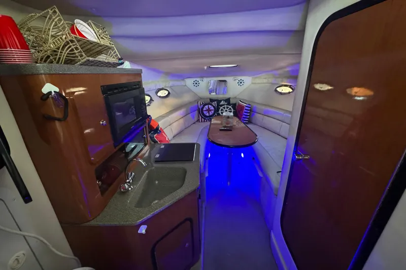 Slide: The Image of Interior of 2003 Crownline 262 CR boat with kitchenette and seating area, illuminated by blue lights. - 38