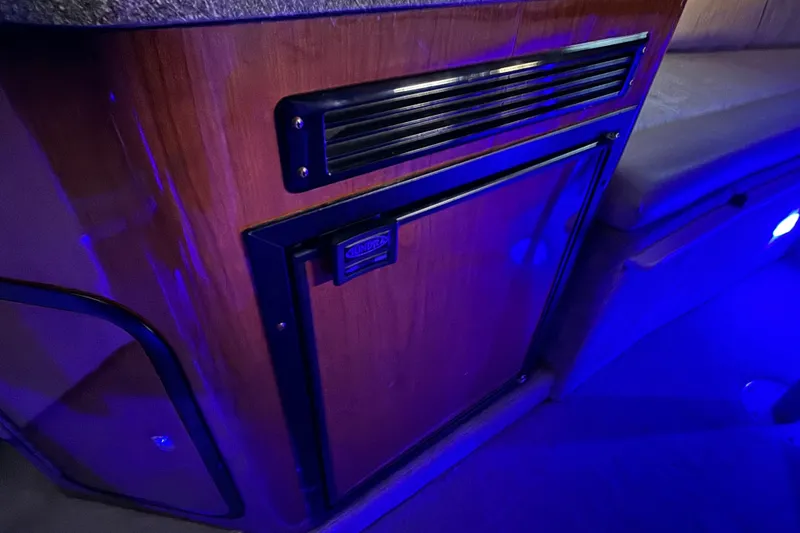 Slide: The Image of 2003 Crownline 262 CR cabin interior with wood paneling and ambient blue lighting. - 46