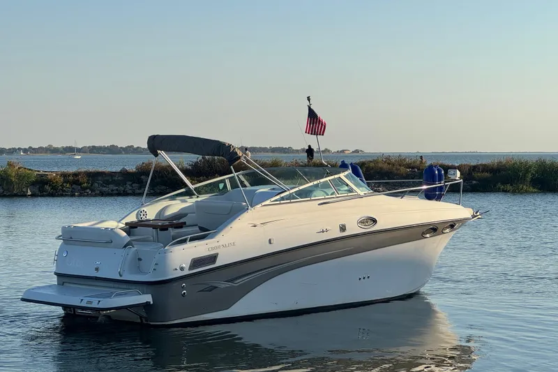 Slide: The Image of 2003 Crownline 262 CR boat on calm water with American flag, scenic background. - 5