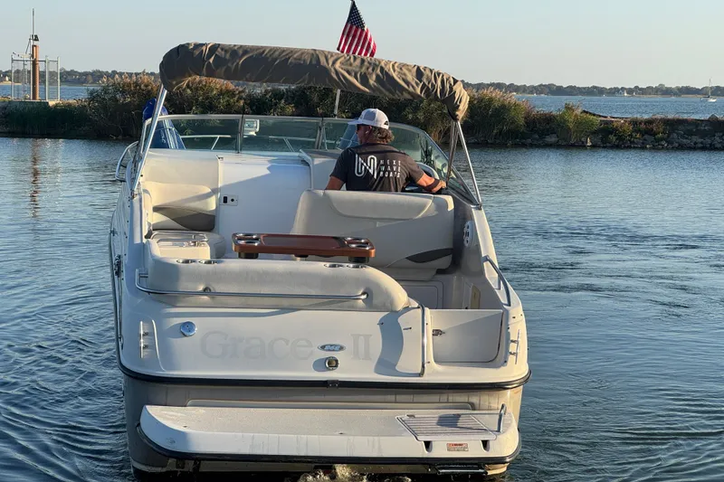 Slide: The Image of 2003 Crownline 262 CR boat cruising on a calm lake with an American flag. - 6