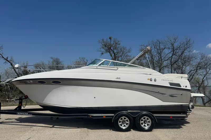 Slide: The Image of 2003 Crownline 262 CR boat on trailer, parked outdoors under clear blue sky. - 7