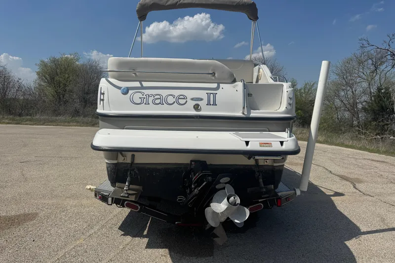 Slide: The Image of 2003 Crownline 262 CR boat named "Grace II" parked on pavement under blue sky. - 9