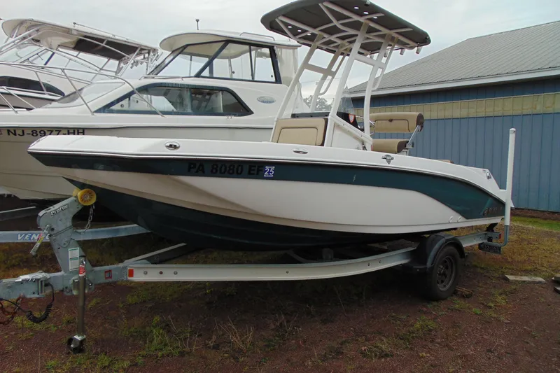 The Image of 2021 Yamaha 195 FSH Sport boat on trailer, parked outdoors near other boats. - 1