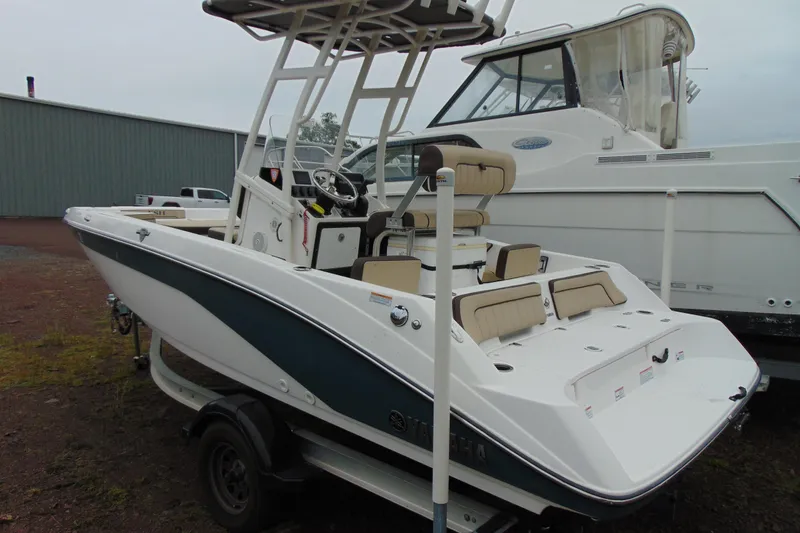 Slide: The Image of 2021 Yamaha 195 FSH Sport boat on trailer, parked near other boats. - 4