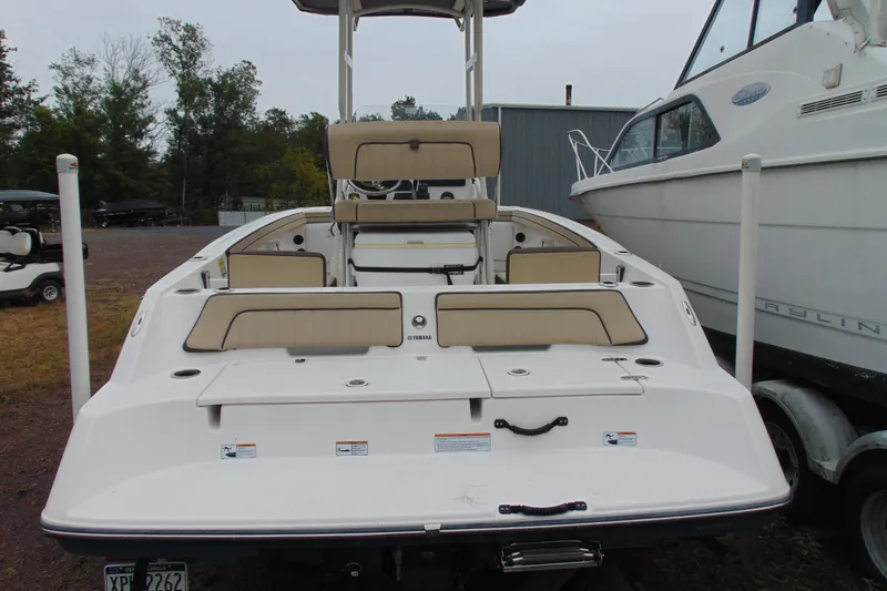 Slide: The Image of 2021 Yamaha 195 FSH Sport boat, rear view, parked beside another vessel. - 5
