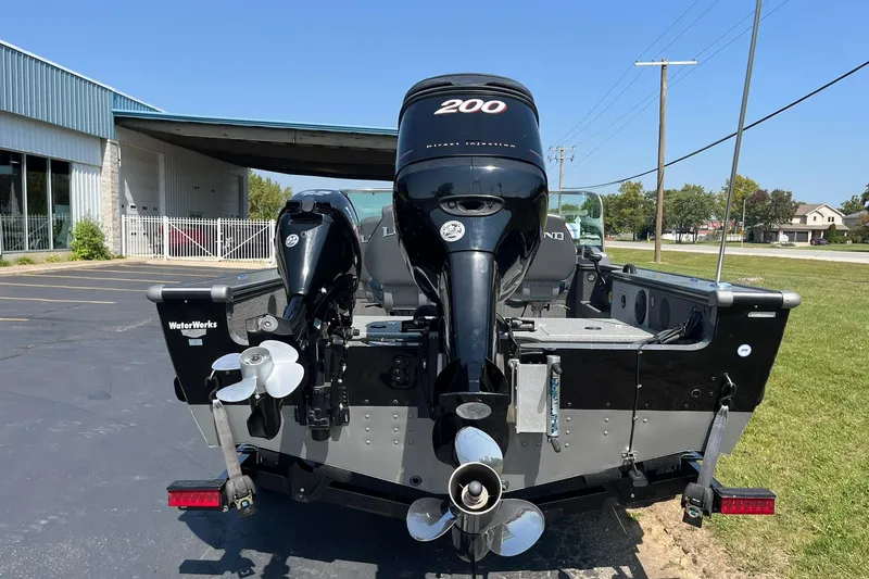 Slide: The Image of 2013 Lund 1875 Pro-V IFS boat with dual outboard motors in a parking lot. - 3