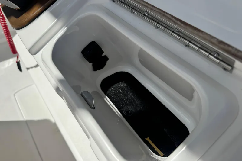 Slide: The Image of Open storage compartment on 2026 Caymas 291 boat, featuring a white interior and metal hinge. - 21