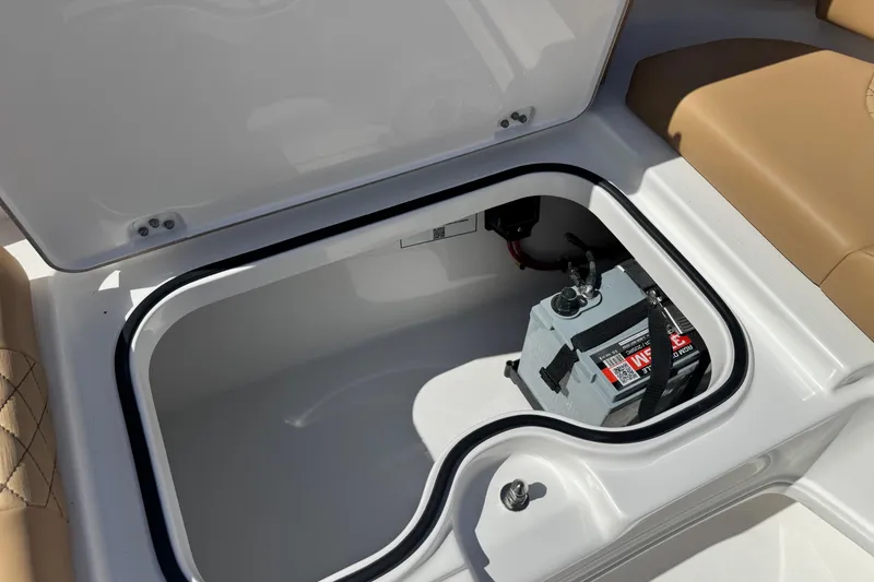 Slide: The Image of 2026 Caymas 291 boat storage compartment with battery, featuring tan seating. - 27