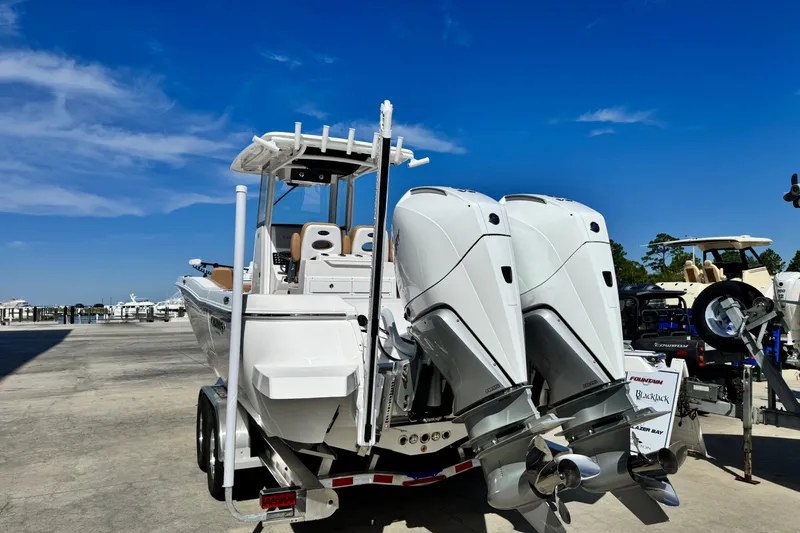 Slide: The Image of 2026 Caymas 291 boat with dual engines on a trailer under a clear blue sky. - 4